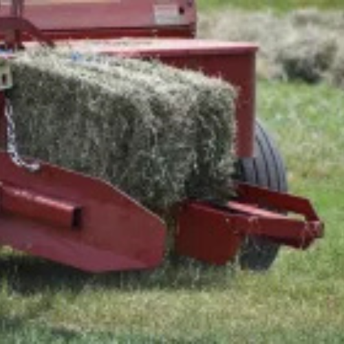 A tractor creating a square bale of hay.